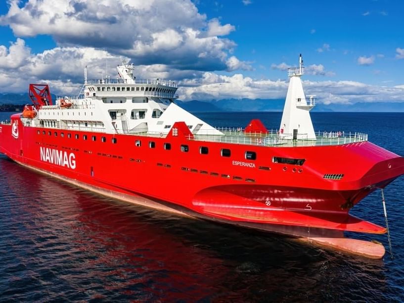 A red cruise ferry sailing in the sea near Hoteles Australis