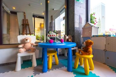 Children's play area with colorful table and plush toys on stools at Metropol Hotel