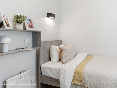 Bedroom with bed, pillows, blanket, wall shelf, and wall light at Mayoral Drive Student Accommodation.