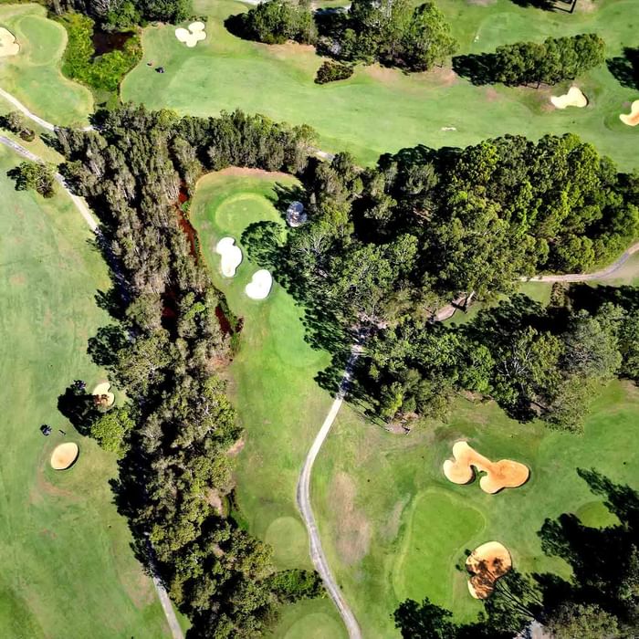 Aerial view of a golf course with ponds, sand bunkers, and a footbridge near Mercure Kooindah Waters
