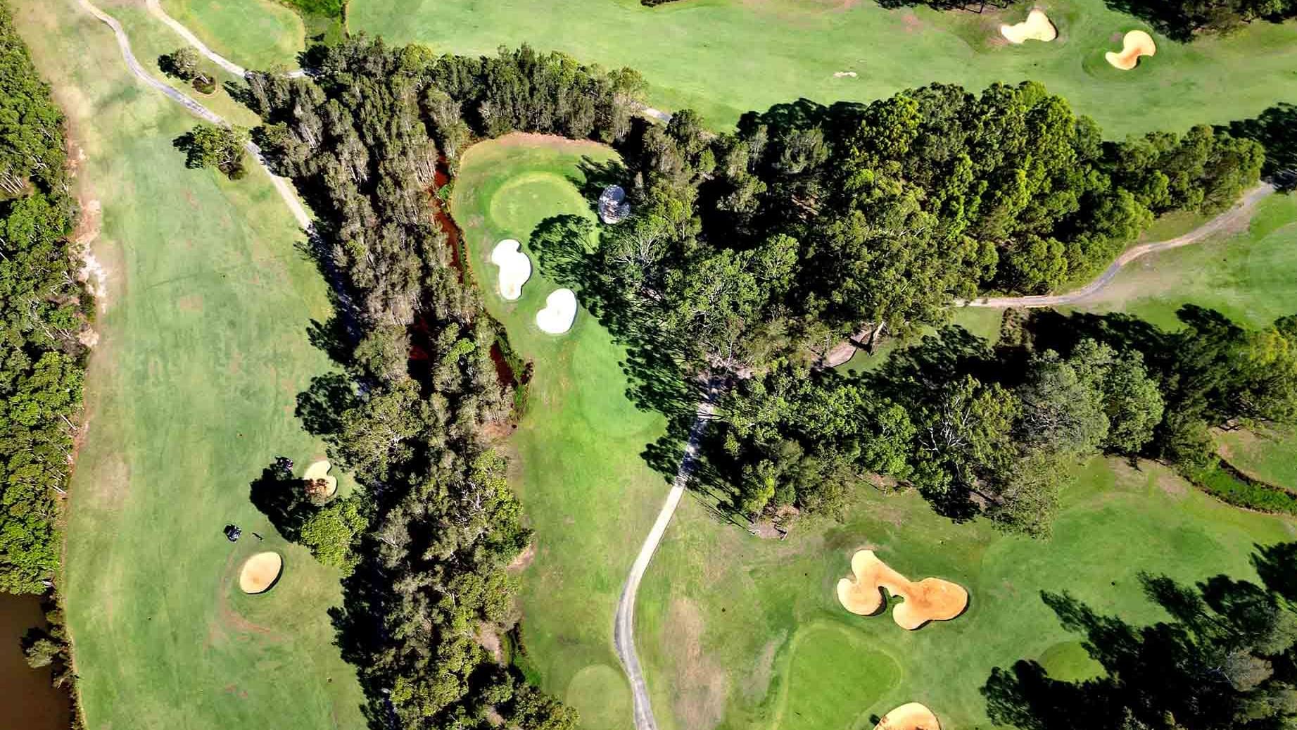 Aerial view of a golf course with ponds, sand bunkers, and a footbridge near Mercure Kooindah Waters