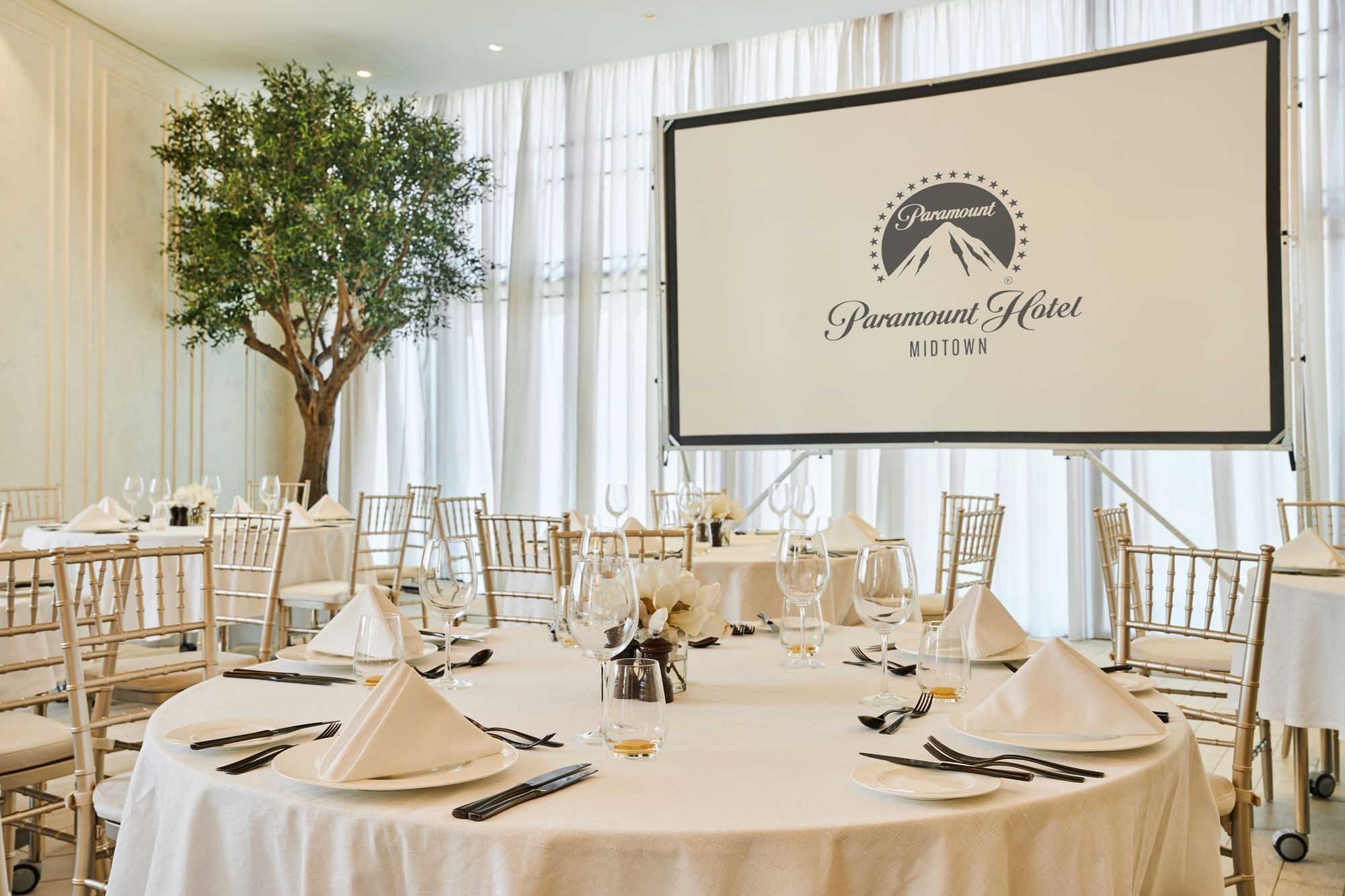 Project screen and table arrangement with Paparazzi restaurant event room at Paramount Hotel