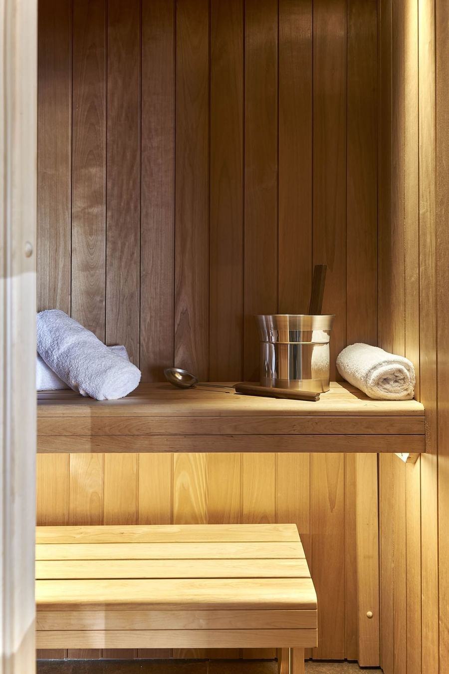 Étagère de sauna en bois avec un seau à vapeur argenté, une louche en bois et une serviette blanche enroulée au Splendid Hotel & Spa de Nice