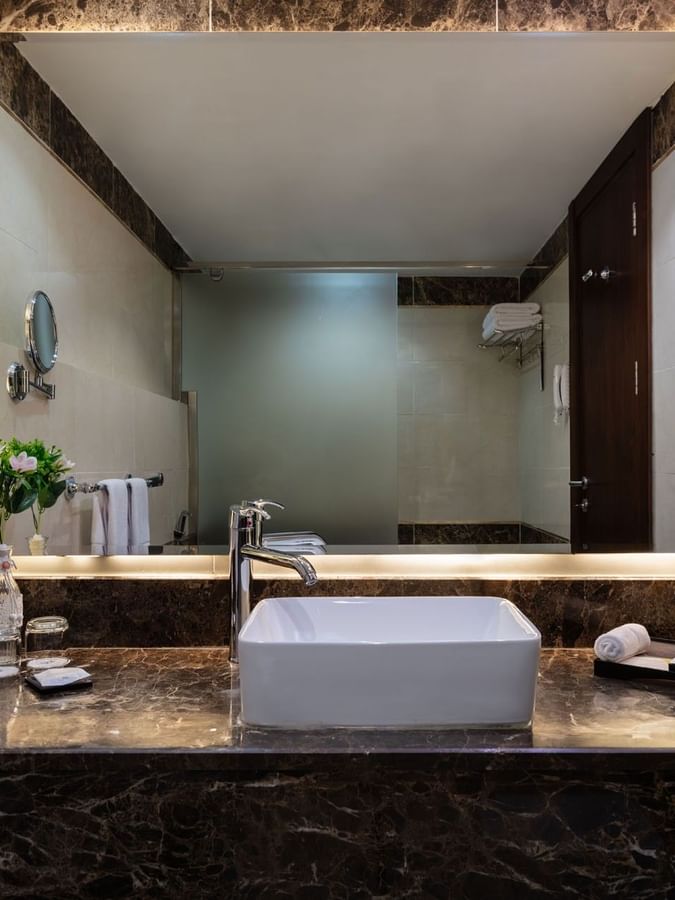 Bathroom vanity with illuminated mirror and amenities in the Deluxe Room at Warwick Hotel Jeddah