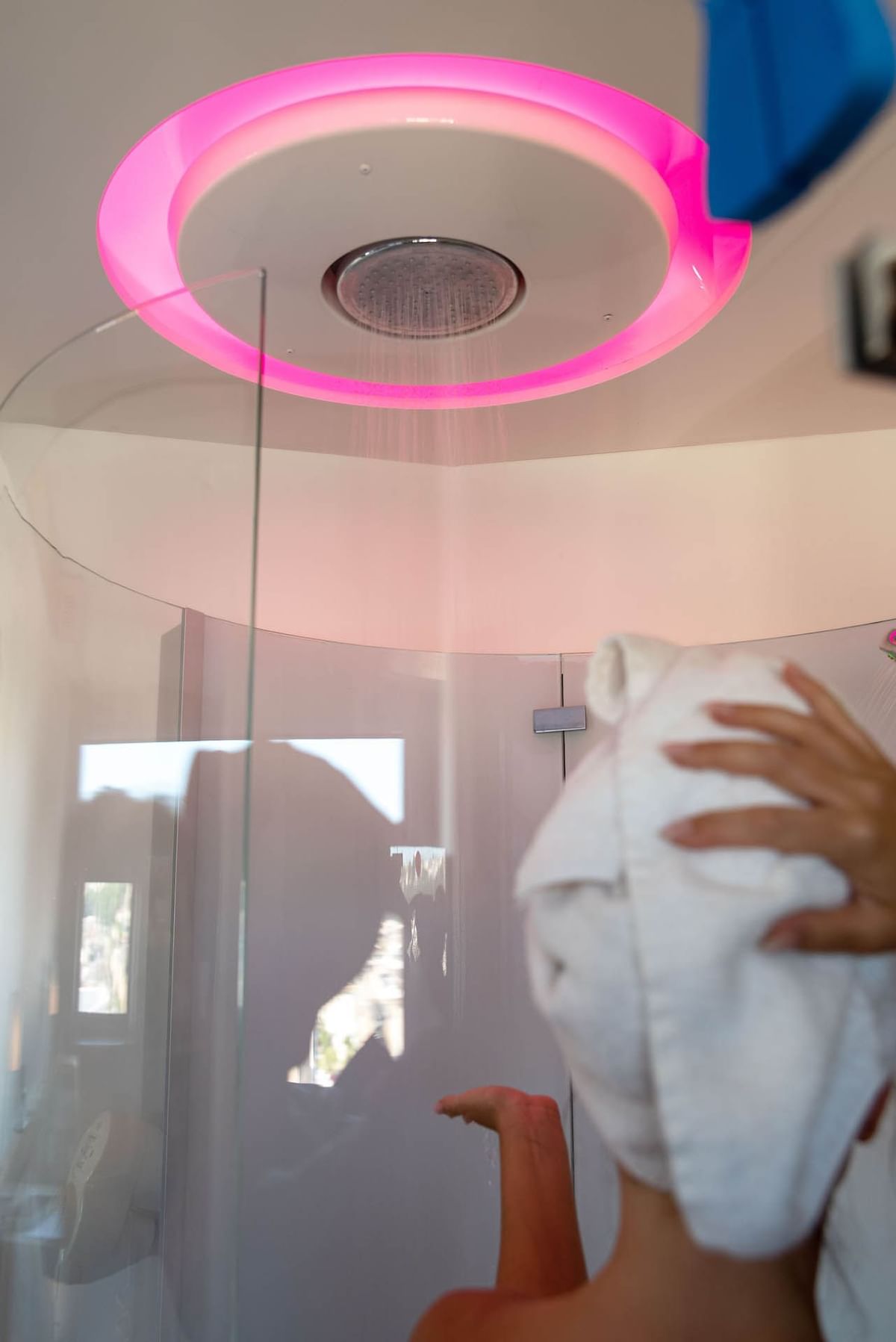 Lady bathing in the shower area of a bathroom at Nomad Hotels