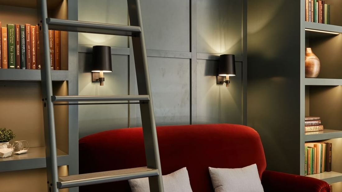 La Biblioteca meeting room at El Prado Hotel, with a red sofa, bookshelves, and ladder