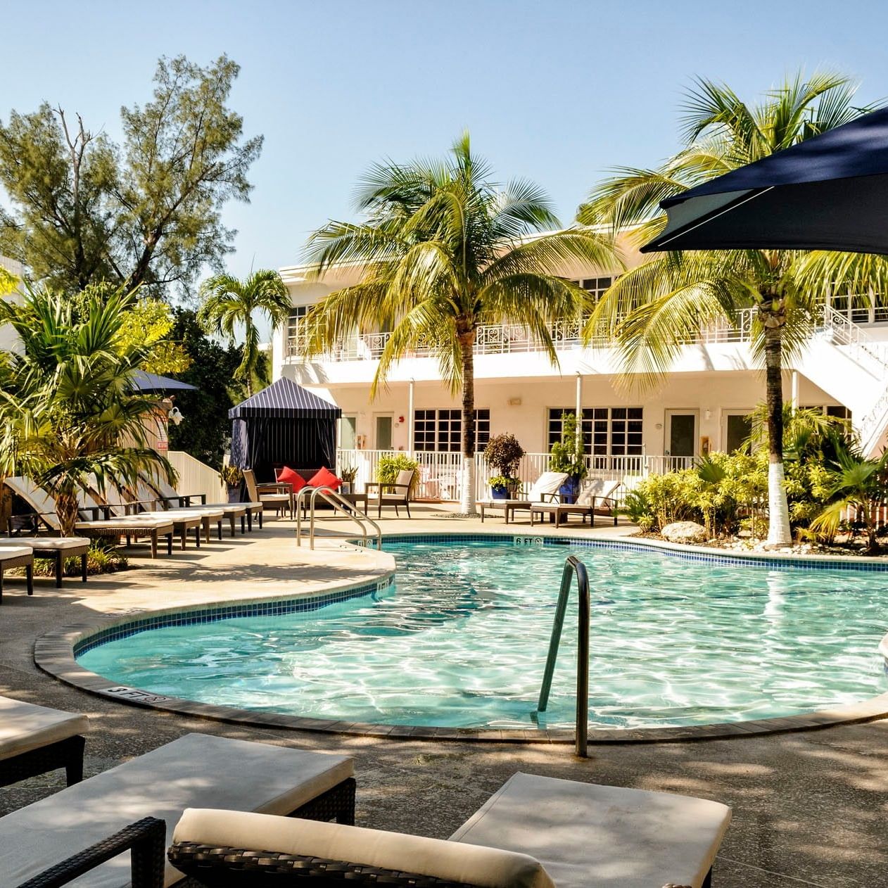 Tropical pool deck with inviting lounge chairs and palm trees surrounding the swimming pool at Tradewinds Apartment Hotel
