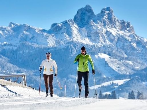 A couple skiing on a hilltop near Liebes Rot Flueh