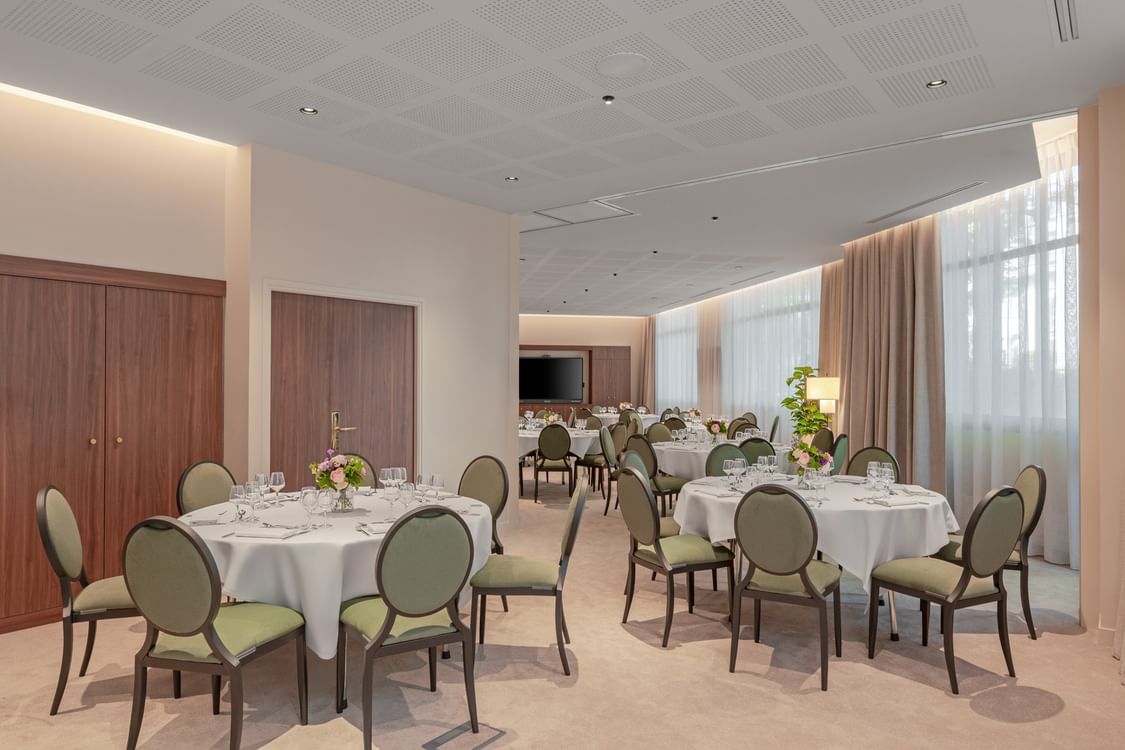 Banquet set-up with wall-mounted TV and soft lighting in the Astrid Salon at Warwick Reine Astrid - Lyon