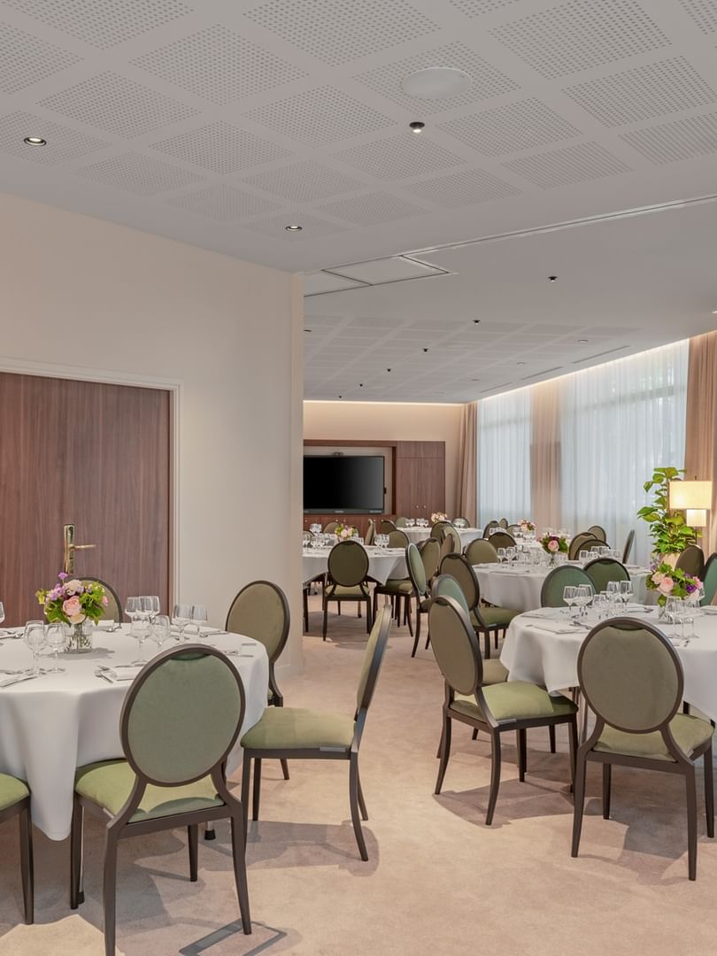 Banquet set-up with wall-mounted TV and soft lighting in the Astrid Salon at Warwick Reine Astrid - Lyon