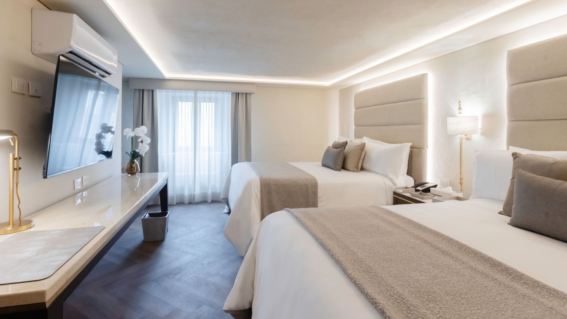 Queen Deluxe room with two beds, white orchids on the desk, and sheer window curtains at Quinta Real Puebla
