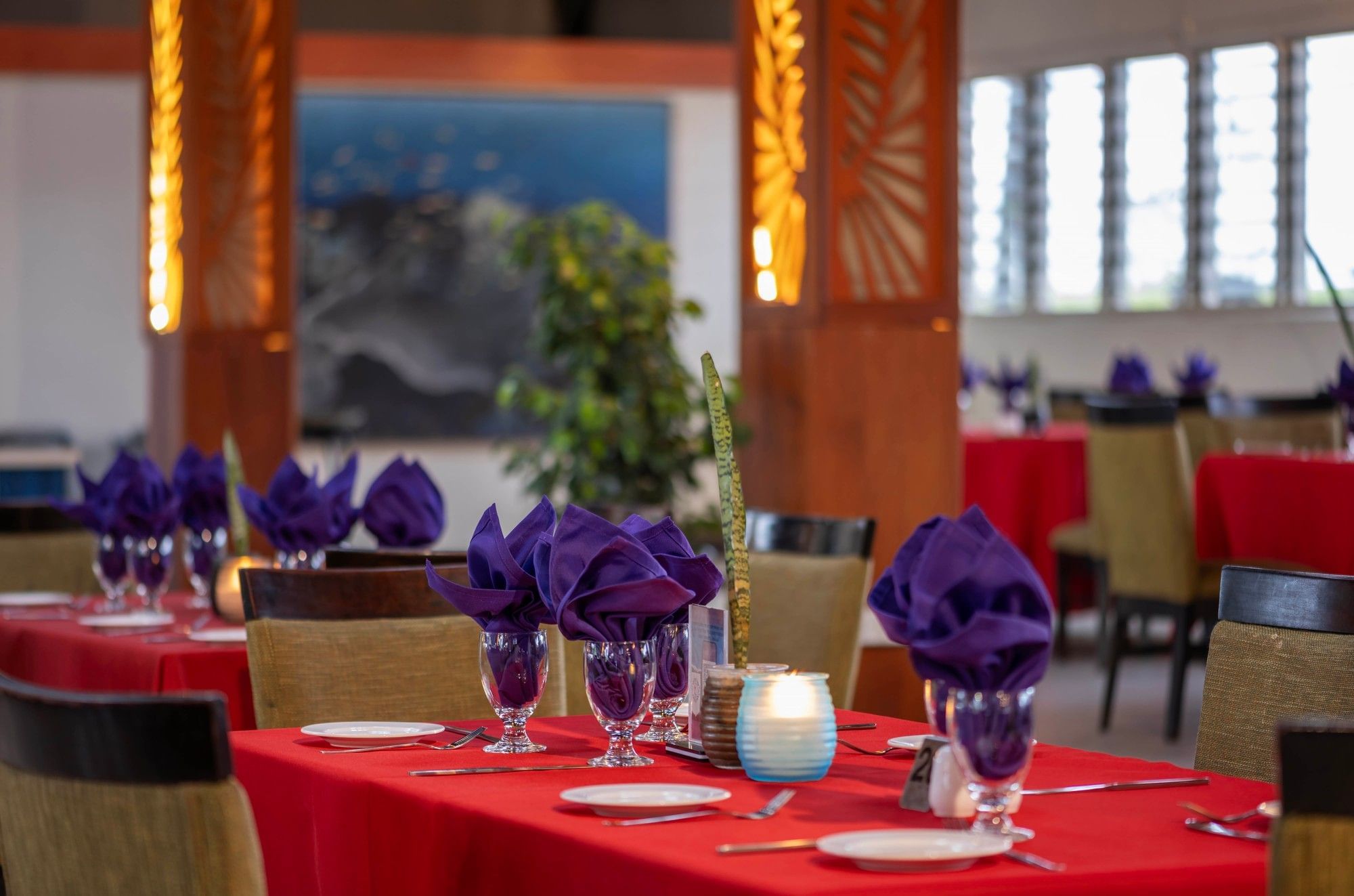 Red-clothed dining tables featuring vibrant purple napkins in KanaVata Restaurant at TokaToka Resort Nadi Fiji