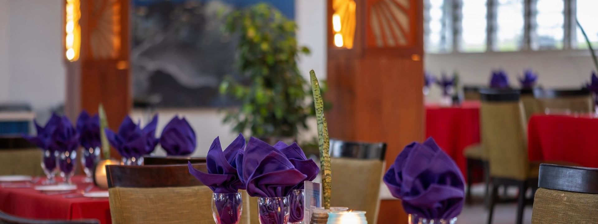 Red-clothed dining tables featuring vibrant purple napkins in KanaVata Restaurant at TokaToka Resort Nadi Fiji