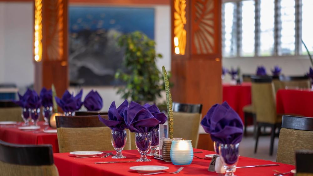 Red-clothed dining tables featuring vibrant purple napkins in KanaVata Restaurant at TokaToka Resort Nadi Fiji