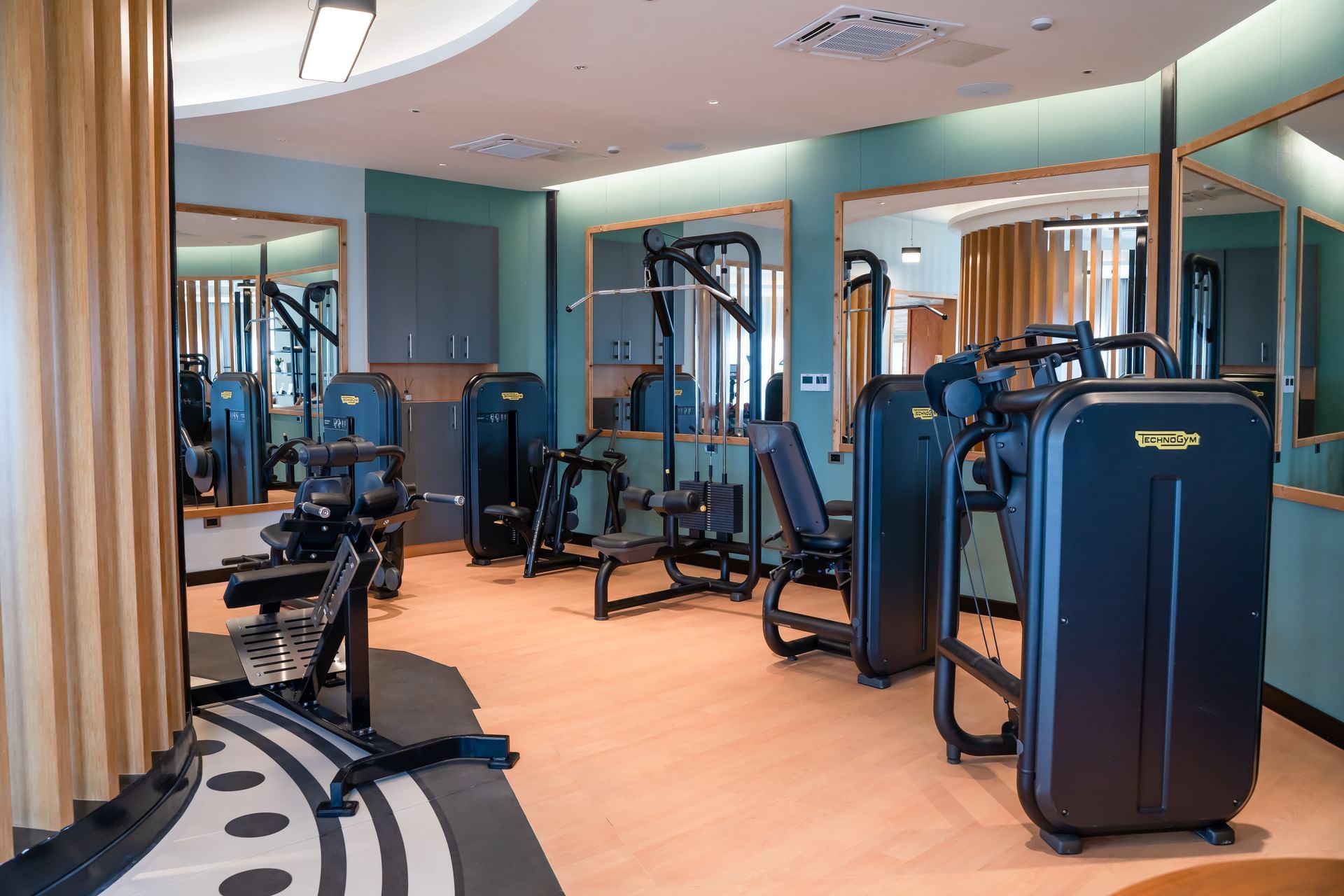Fitnessruimte met Technogym-apparaten voor de spiegels en houten accenten bij Golden Rock Resort