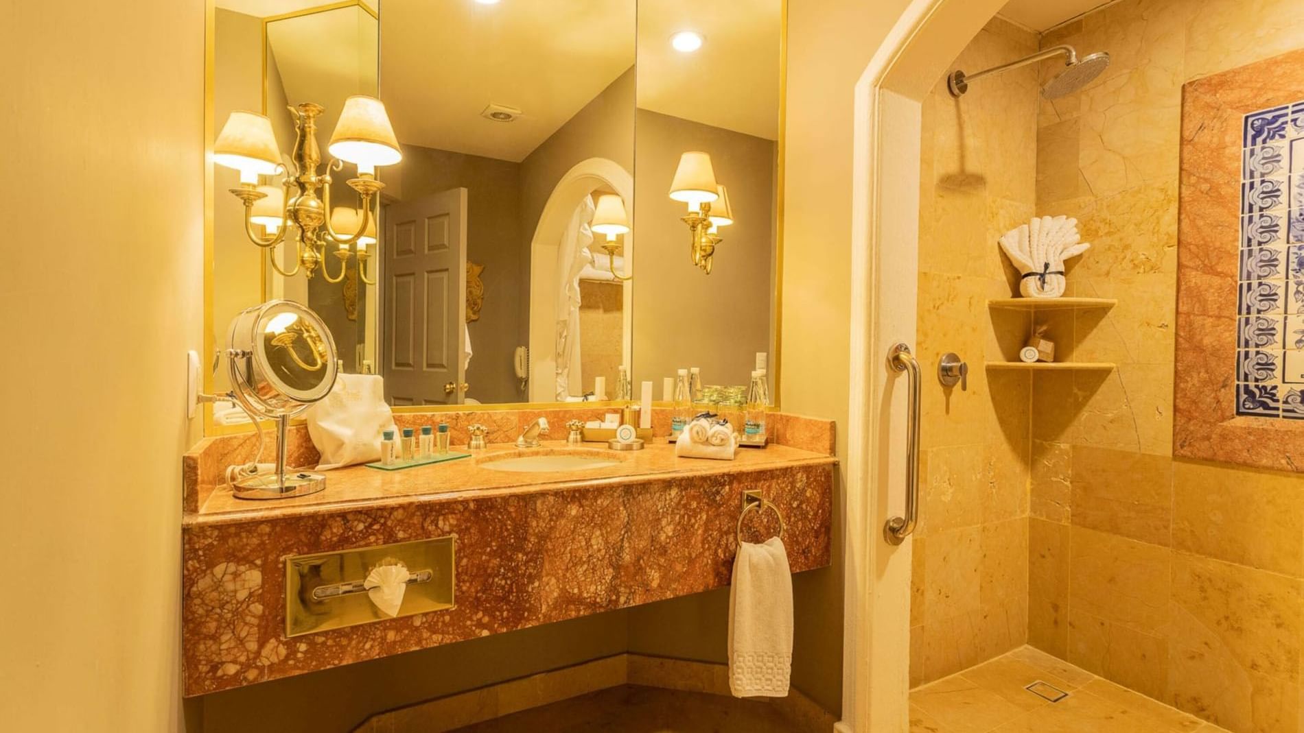 Modern walk-in shower in King Master Suite featuring tan stone tiles and a premium marble sink area at Quinta Real Monterrey