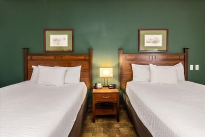 Two queen beds with a nightstand in Double Queen ADA at Boothill Inn & Suites