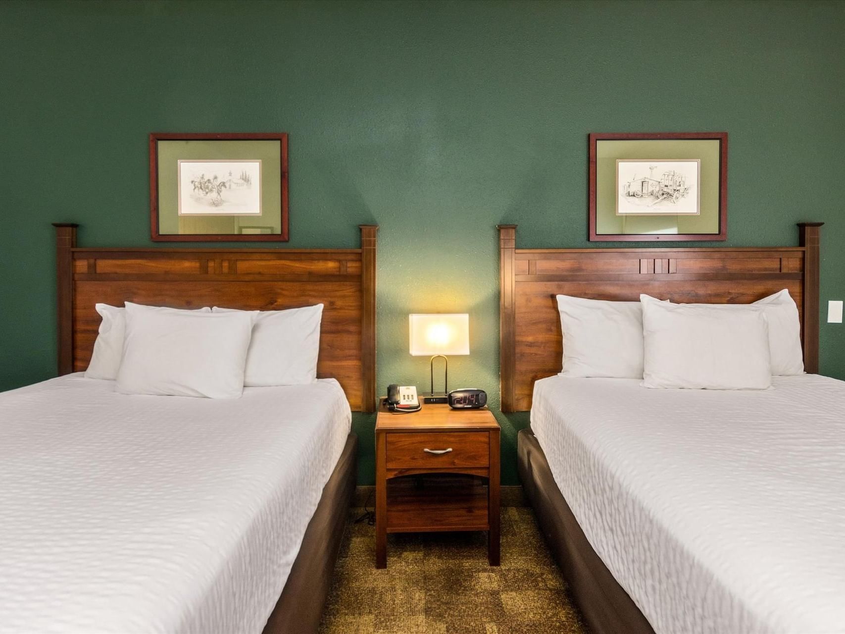 Two queen beds with a nightstand in Double Queen ADA at Boothill Inn & Suites