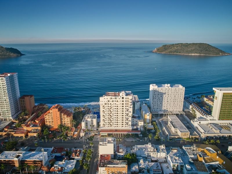 High-angle aerial view of a coastal city skyline featuring beachfront hotels & islands in the ocean near Sunvivia Mazatlán