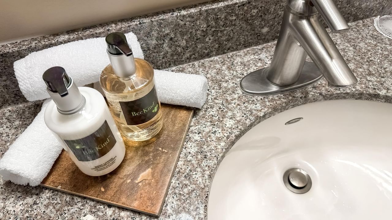 Lotion, soap, and towels by the hotel bathroom sink