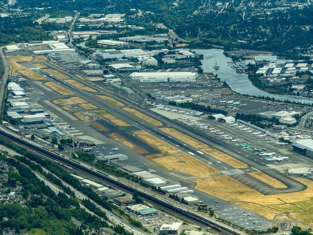 Aerial view of an airport runway by rows of parked planes under a hazy sky near Warwick Seattle