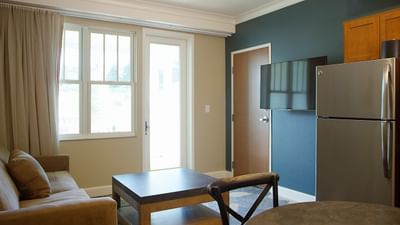 A modern living area in a room at The Stanley Hotel, with a small sofa and a kitchenette with a refrigerator