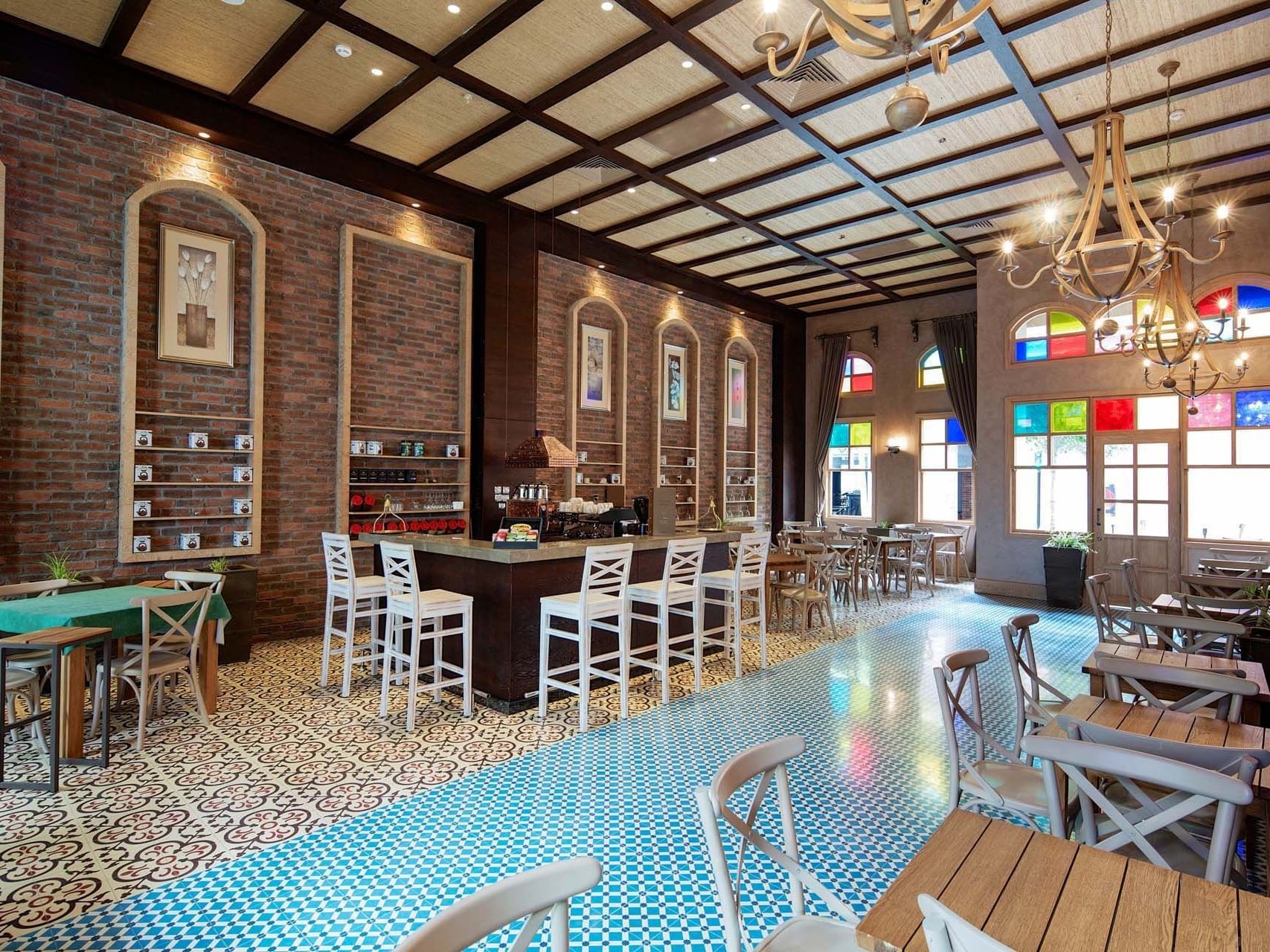 Café interior with brick walls, wooden tables, and bar counter at Titanic Deluxe Golf Belek