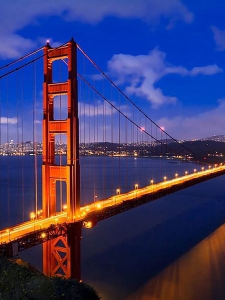 Golden Gate Bridge by a misty city skyline under a vibrant orange sunset near Warwick San Francisco