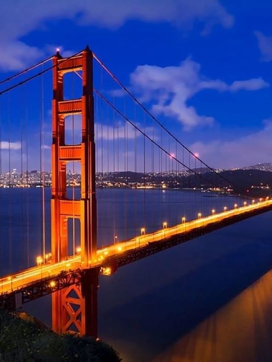 Golden Gate Bridge by a misty city skyline under a vibrant orange sunset near Warwick San Francisco