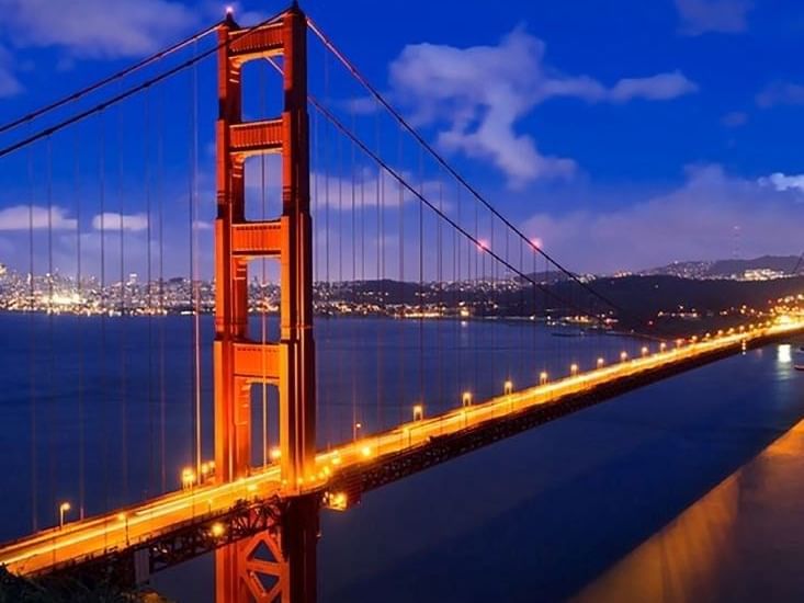 Golden Gate Bridge by a misty city skyline under a vibrant orange sunset near Warwick San Francisco