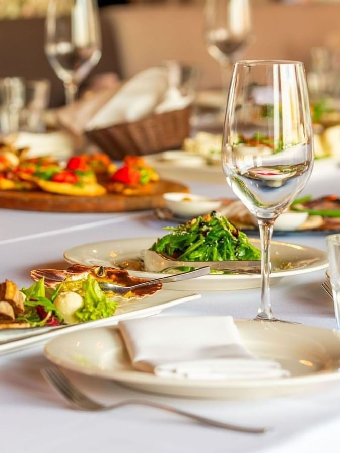 Fine dining table with gourmet plates and wine glasses on a white cloth in Sunday Brunch at Warwick Geneva