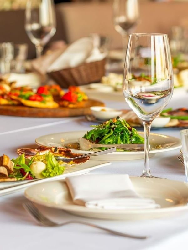 Fine dining table with gourmet plates and wine glasses on a white cloth in Sunday Brunch at Warwick Geneva