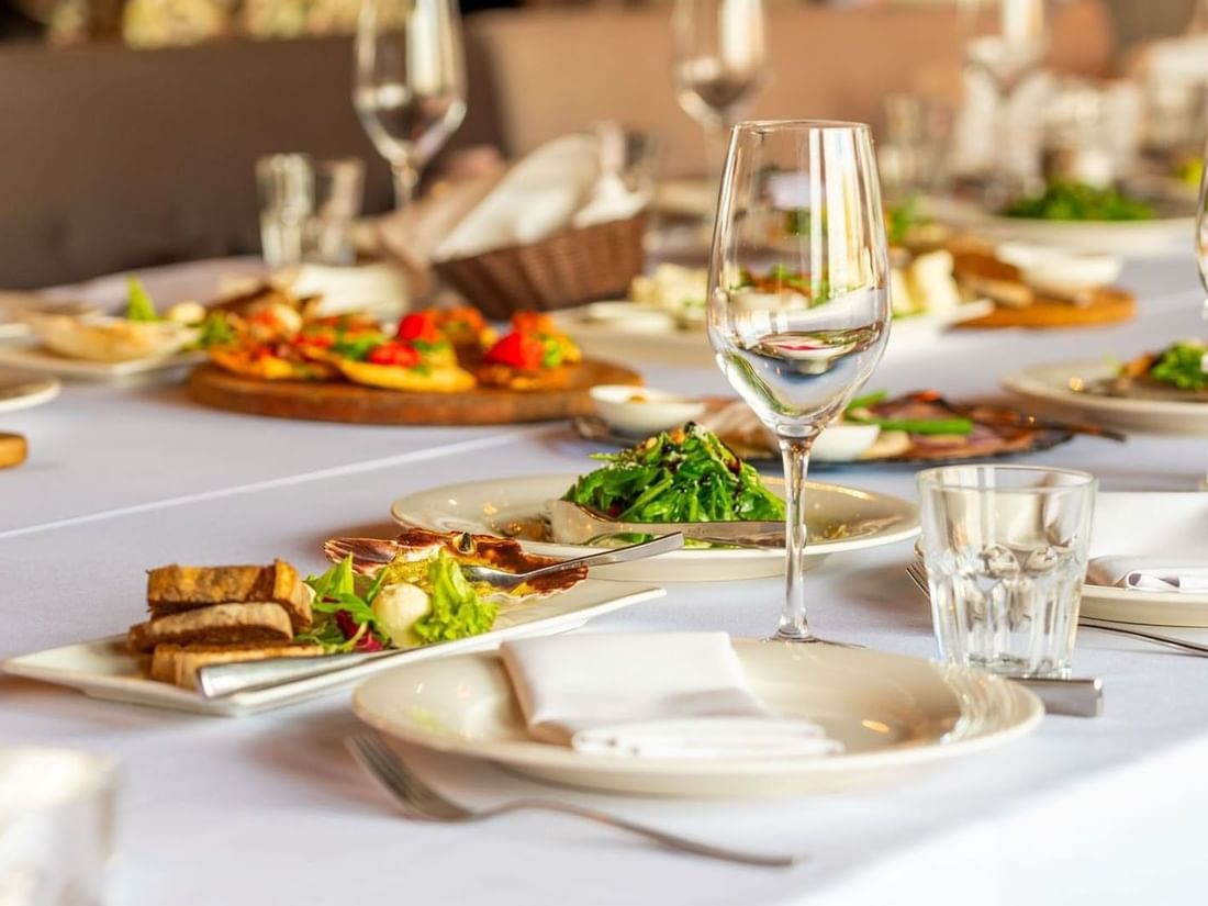 Fine dining table with gourmet plates and wine glasses on a white cloth in Sunday Brunch at Warwick Geneva