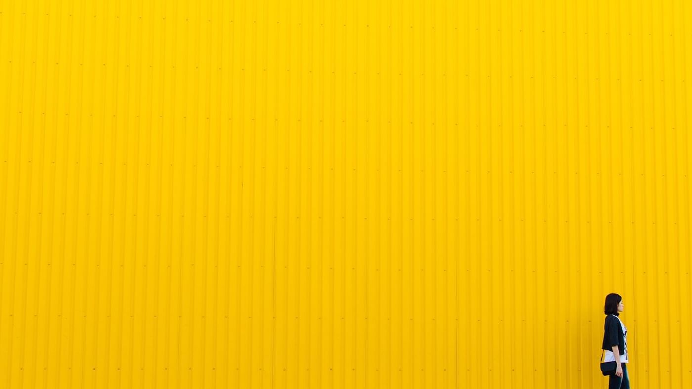 A lady walking on a yellow background at Crown Hotels
