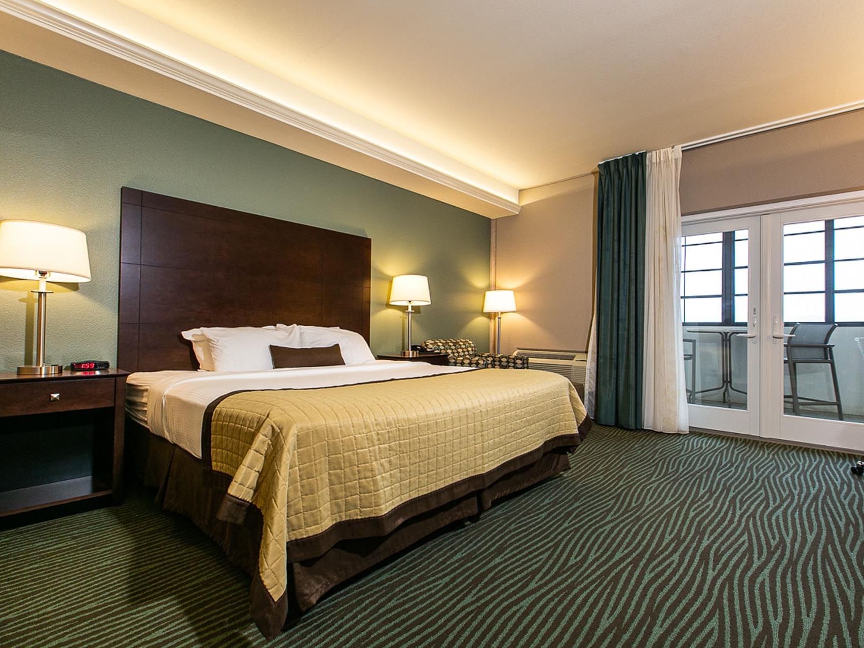 Cozy bed with lamps and carpeted floor in King River View at Off Shore Resort