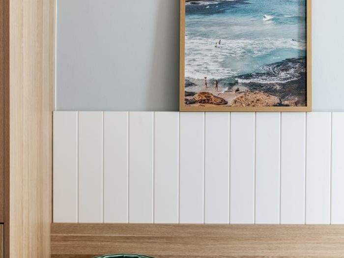 Ocean View Twin at Elysium Manly with framed ocean photography by a wooden wardrobe door under a soft blue paneled wall