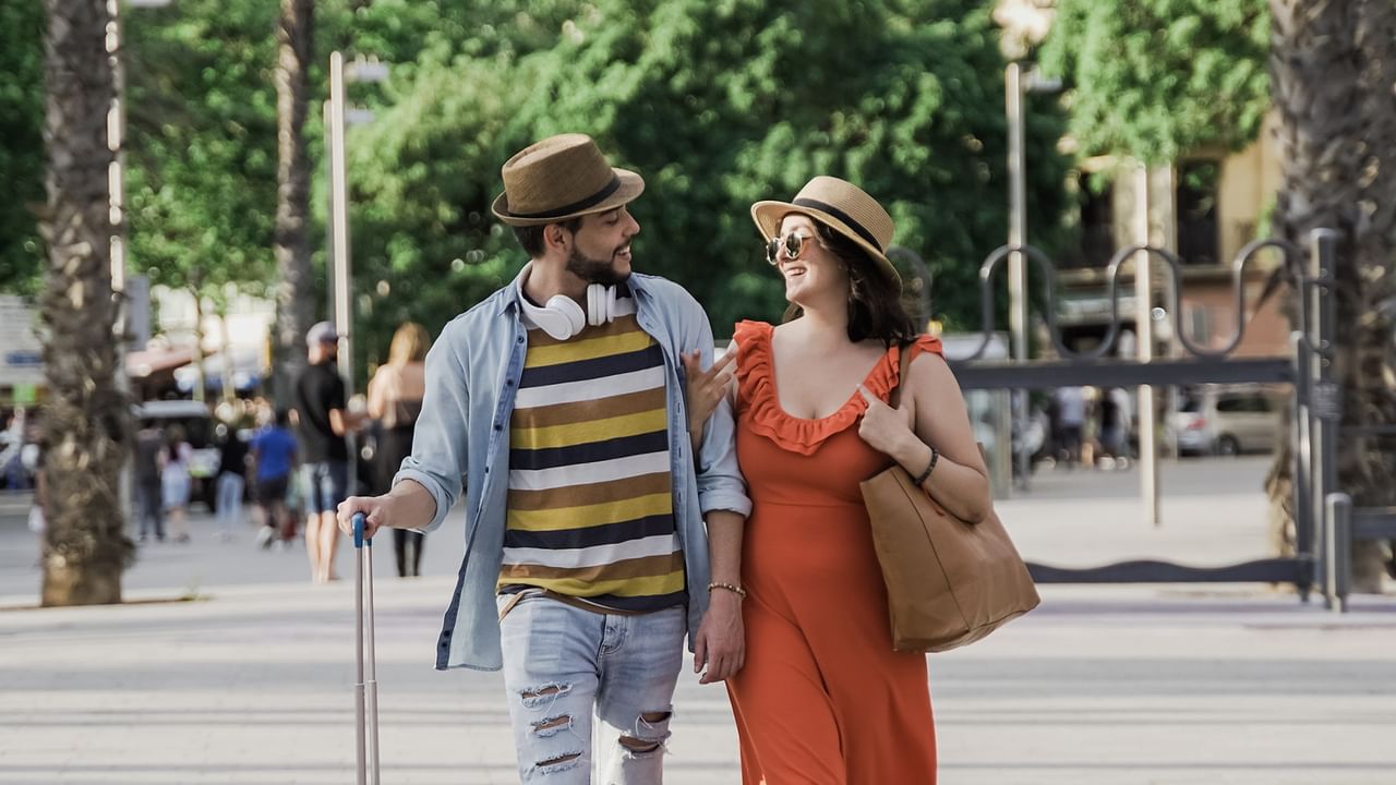 Couple walking with luggage in a city.