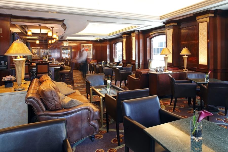 Elegant hotel lobby with rich wood paneling, leather seating, and warm lighting at Warwick New York