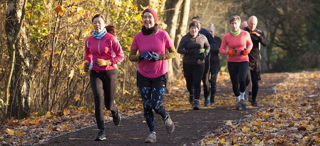 people jogging together on a leaf covered road