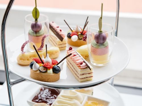 A three-tiered stand filled with assorted elegant pastries and desserts in Restaurant Cuvée at Sofitel Brisbane Central