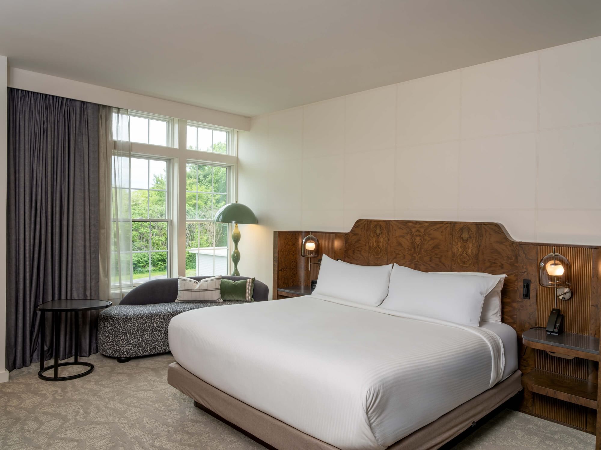 The sky king guest room with a bed, nightstands, a couch, and a large window with curtains.