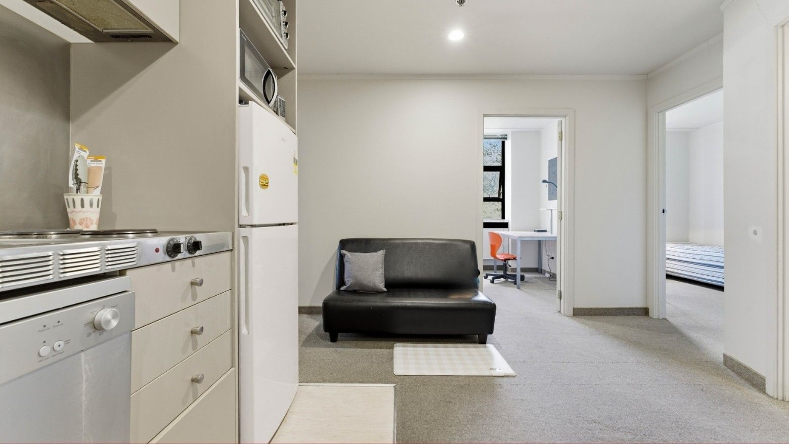 Small kitchen area with refrigerator, stove, and cabinets at UniLodge Stafford House.