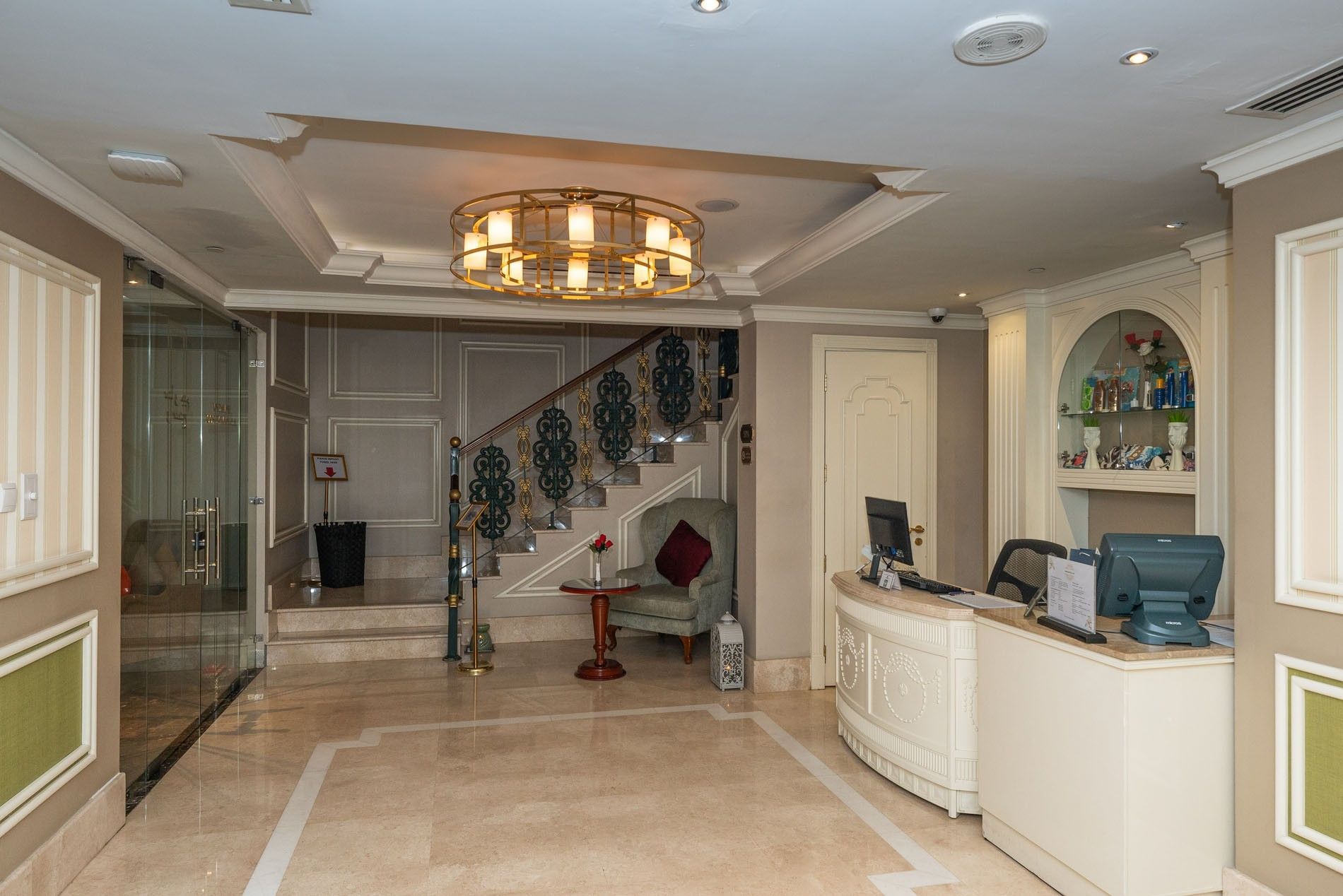 Curved reception desk by a wingback chair under a gold ring chandelier in the spa lobby at Warwick Doha Hotel