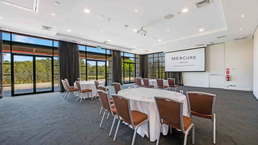 Kooindah Three conference room with tables, chairs, and large windows overlooking trees at Mercure Kooindah Waters