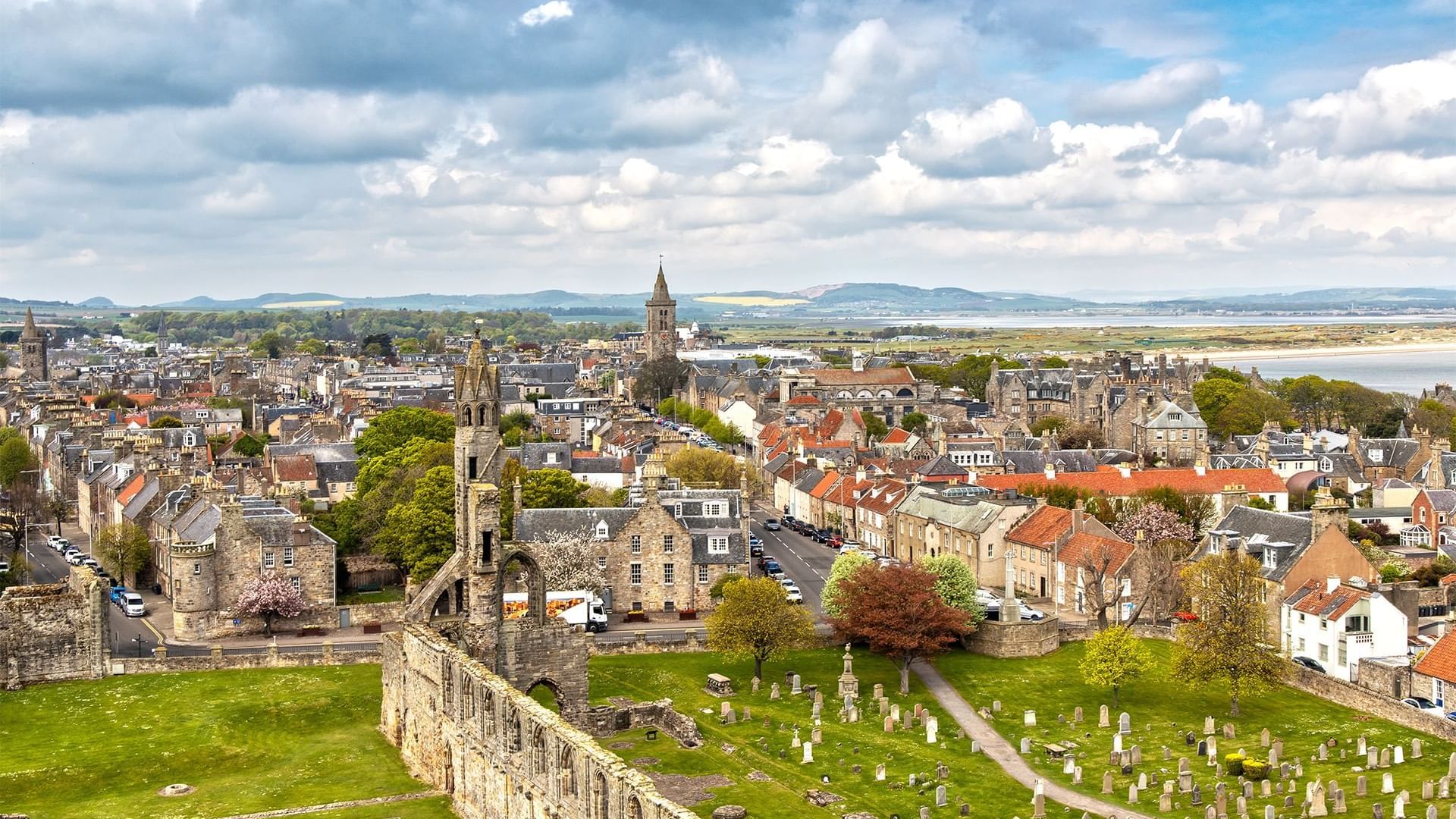 Aerial view of St Andrews Cathedral with graves, & a seascape in the distance near Seaton House