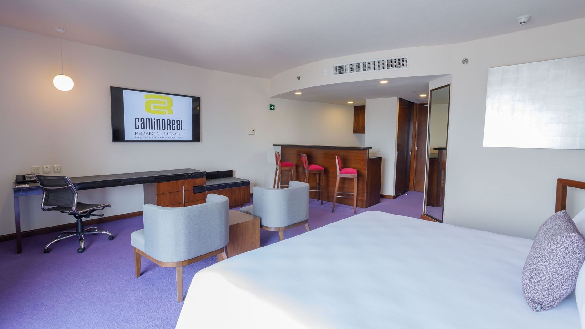 Elegant King Junior Suite at Camino Real Pedregal Mexico, featuring a private bar area with tall red stools