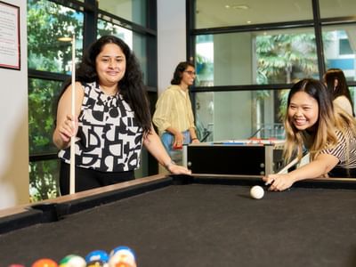 Two residents playing pool at Student Living - 800 Swanston.