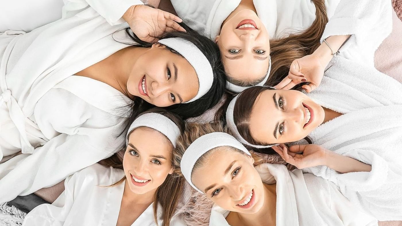 Ladies in oversized shirts laying down on the bed at Fiesta Americana Travelty