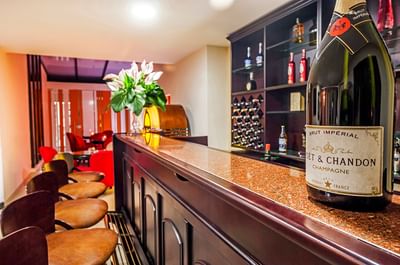 Wine shelves in a bar counter area with high stools at Le Manoir Bogotá Hotel