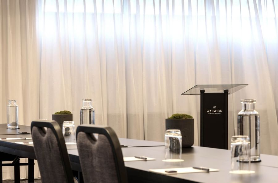 Black lectern with hotel branding by table settings in Salon René-Lévesque at Warwick Le Crystal Montreal